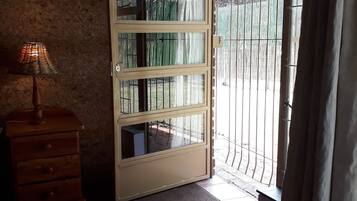 A room with a large sliding glass door leading to an outdoor area with a bamboo fence.