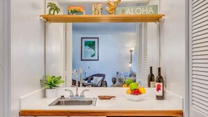 A kitchen with a wooden countertop, a sink, a dish rack with fruits, and a dish soap bottle.