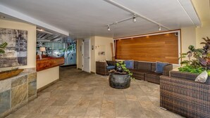 A spacious lobby with a reception desk, wicker furniture, and a large wooden door.