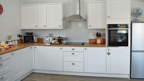 Una cucina moderna con mobili bianchi, un forno a microonde, un tostapane e un frigorifero.