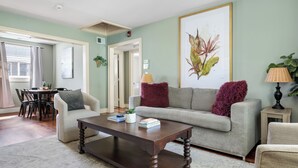A living room with a sofa, armchairs, a coffee table, and a dining area with chairs and a table. - Easy Walk to King Street! | Casa Fuego Suite E (Charleston)