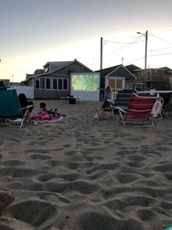 Una playa con sillones de descanso y una pantalla de proyección.