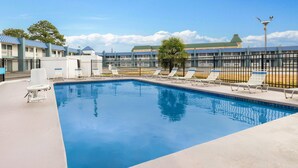 A swimming pool with lounge chairs and a fenced area, surrounded by buildings with a green roof. - Super 8 by Wyndham Portsmouth - Norfolk (Portsmouth)