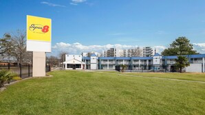 A hotel with a large yellow sign, modern buildings, and a grassy area. - Super 8 by Wyndham Portsmouth - Norfolk (Portsmouth)