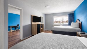 A hotel room with a large bed, a desk with a chair, a TV, and a window with curtains. - Super 8 by Wyndham Portsmouth - Norfolk (Portsmouth)