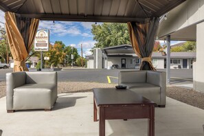 An outdoor seating area with two sofas and a table, a covered patio, and a sign for Oregon Trail Inn & Suites.