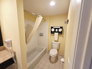 A bathroom with a bathtub, toilet, and a towel rack with towels.