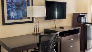 A hotel room with a desk, chair, television, and a framed artwork on the wall. - Oregon Trail Inn and Suites (Lakeview)