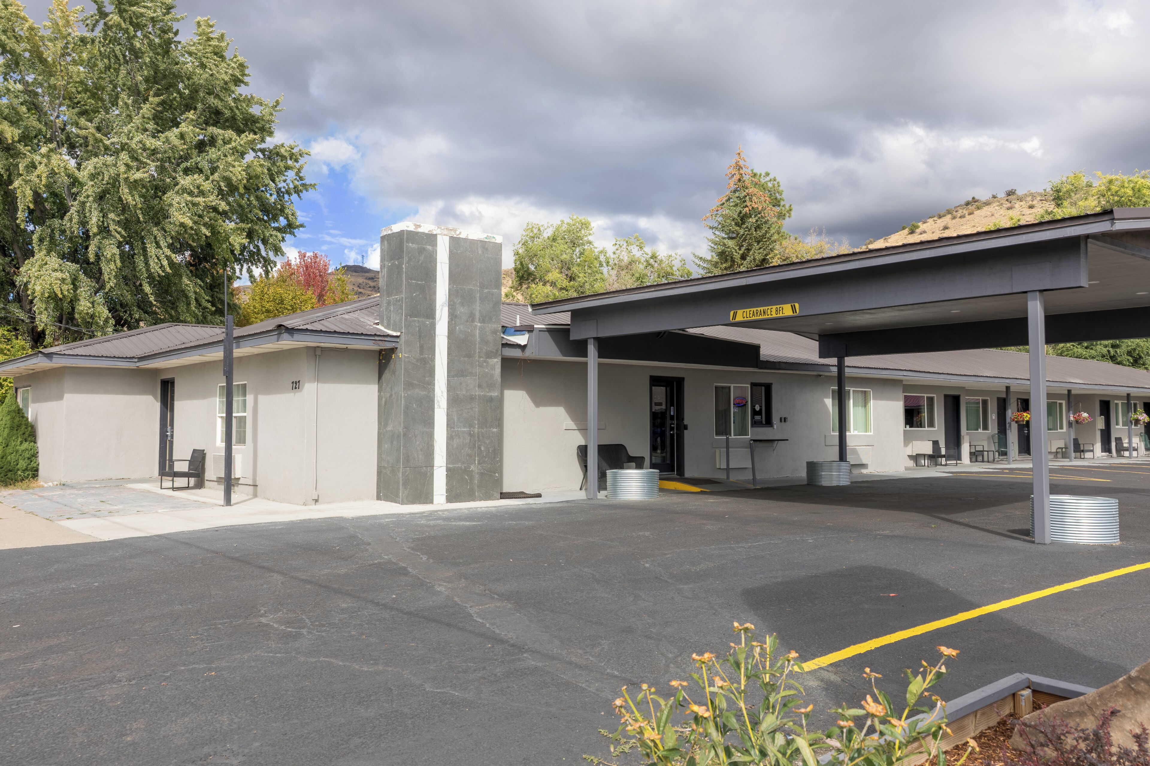 A hotel with a covered parking area, a sign indicating a clearway, and a building with a grey facade.
