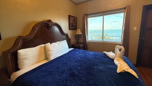 A bed with a blue quilt, white pillows, and a towel shaped like a swan.