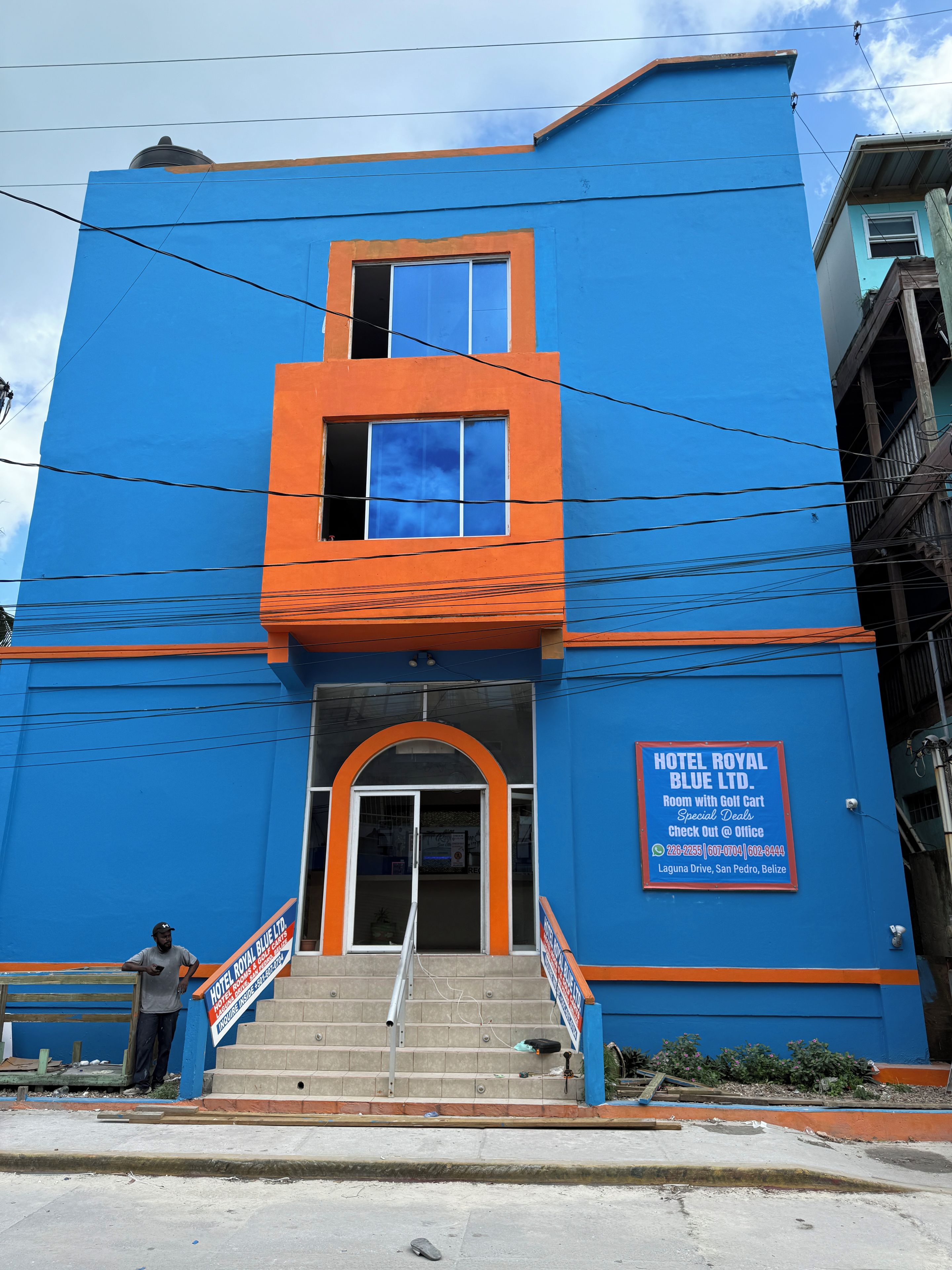 Un hotel con fachada azul, una escalera que lleva a la entrada y un cartel anunciando ofertas especiales.