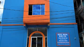 Un hotel con fachada azul, una escalera que lleva a la entrada y un cartel anunciando ofertas especiales.