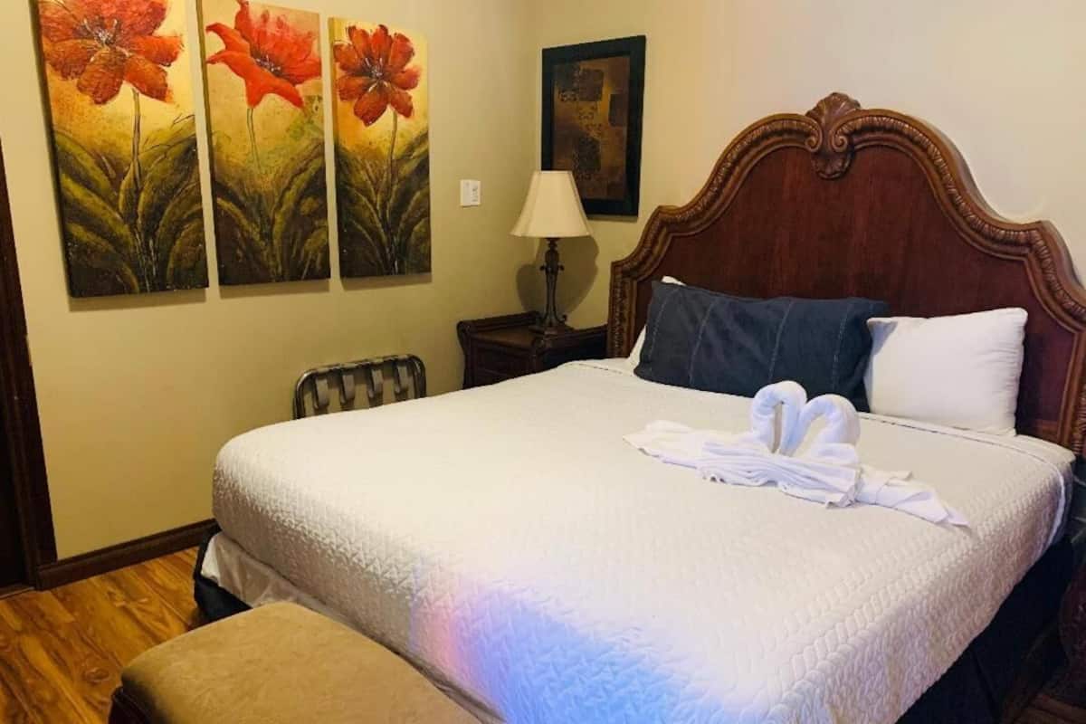 A neatly made bed with a white quilt, a wooden headboard, and a bench at the foot of the bed.
