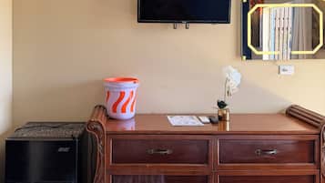Una habitación con un aparador de madera, un televisor montado en la pared, una mesita con un florero y un banco.