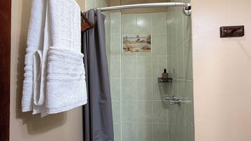 Un baño con ducha, un perchero con toallas y un cortinón de ducha.