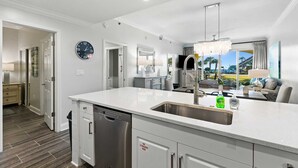 A modern kitchen with a central island, stainless steel appliances, and a view of the outdoors. - Modern Upscale Condo Ground floor with easy beach access. Beach Service included $60 day Value! (Miramar Beach)