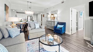 A modern living room with a sofa, armchairs, a coffee table, and a dining area with a chandelier. - Modern Upscale Condo Ground floor with easy beach access. Beach Service included $60 day Value! (Miramar Beach)