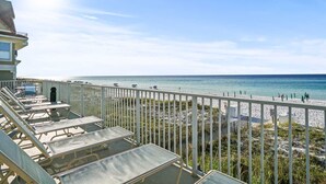 A balcony with sun loungers overlooking a beach with a clear sky. - Modern Upscale Condo Ground floor with easy beach access. Beach Service included $60 day Value! (Miramar Beach)
