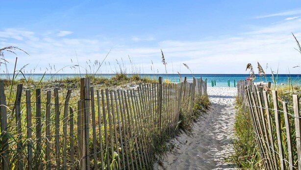 A sandy beach path with wooden fencing and vegetation, leading to a beach with clear blue water. - Modern Upscale Condo Ground floor with easy beach access. Beach Service included $60 day Value! (Miramar Beach)