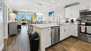 A modern kitchen with white cabinetry, a large island, stainless steel appliances, and a view to the outdoors. - Modern Upscale Condo Ground floor with easy beach access. Beach Service included $60 day Value! (Miramar Beach)