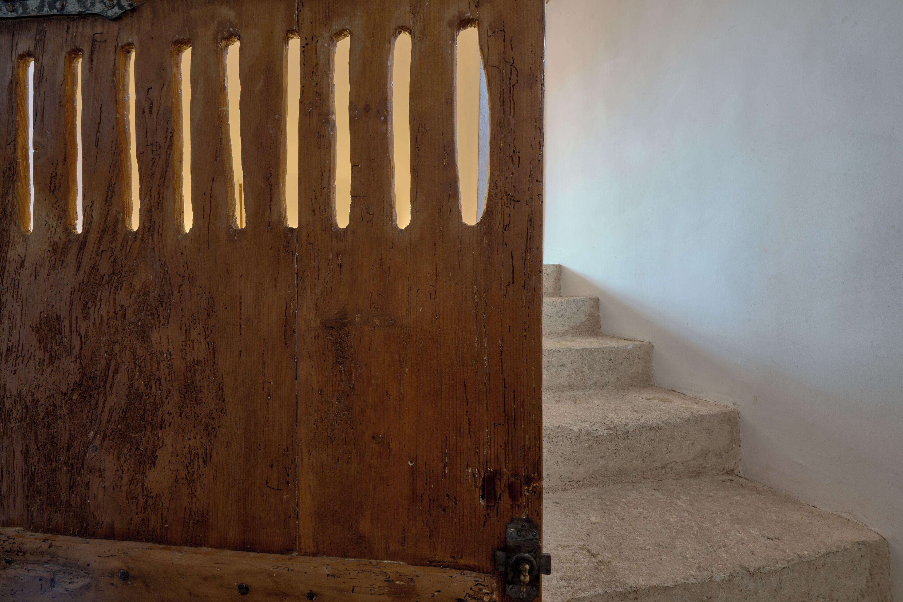 A wooden door with vertical slits and a metal latch.