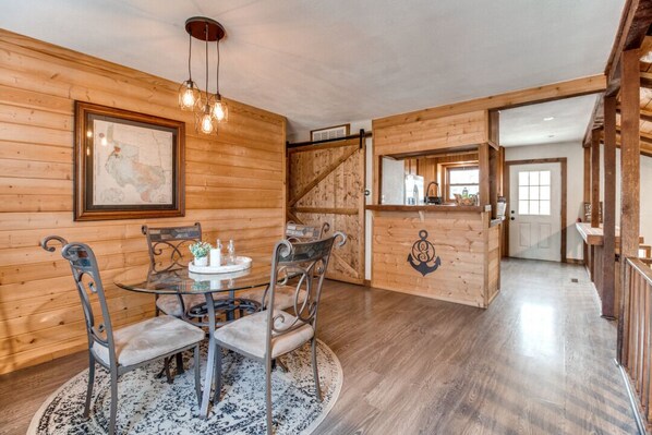 A wooden interior with a dining table and chairs, a staircase, and a kitchen area. - The Barrel House on Lake Texoma (Pottsboro)