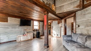Un salon spacieux doté de planchers en bois, d’un canapé gris, d’une table basse en bois et d’un téléviseur fixé au mur.