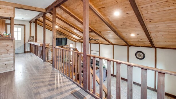 Un intérieur spacieux avec des poutres en bois, un escalier et une vue sur l’extérieur.
