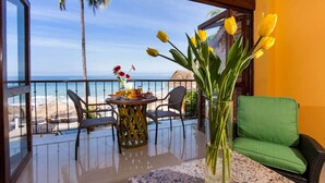 Un balcón con una mesa dispuesta para el desayuno, con vista a la playa y el océano.