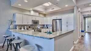 Una cocina moderna con armarios blancos, encimera de granito y electrodomésticos de acero inoxidable.