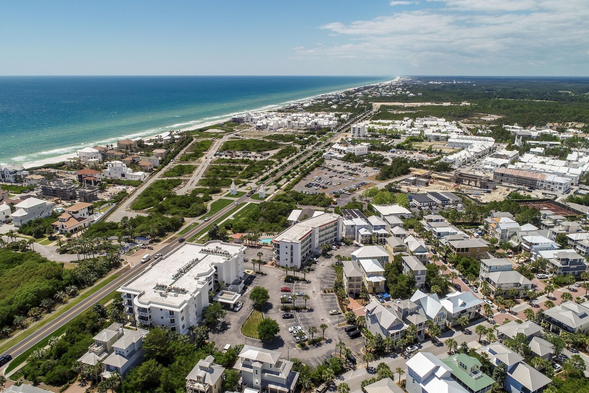 An aerial view of a coastal residential area with buildings, roads, and a beach.