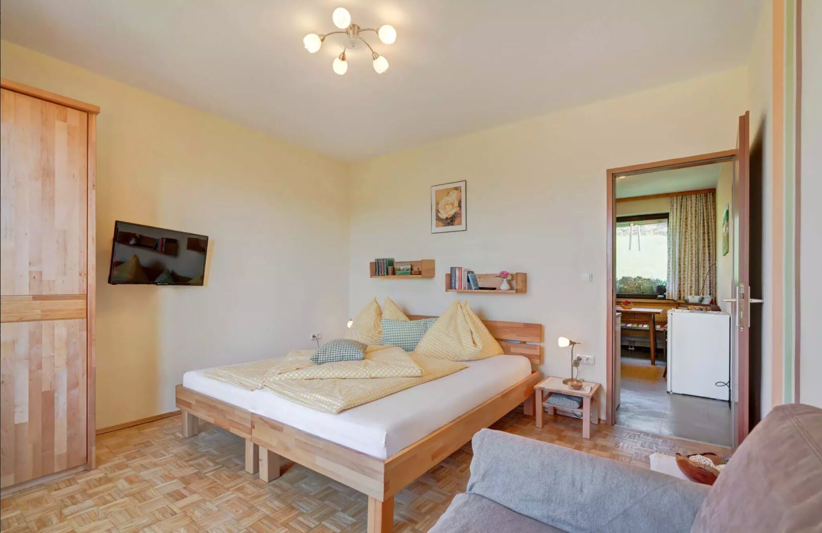 A bedroom with a bed, bedside table, and a television mounted on the wall.