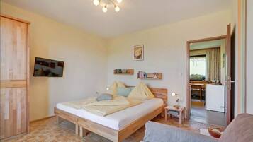 A bedroom with a bed, bedside table, and a television mounted on the wall.