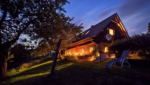 A wooden cabin with a sloped roof, a porch, and a chair outside.