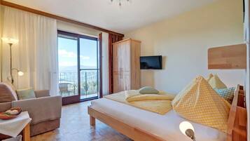 A modern bedroom with a large bed, a TV, and a balcony with a view.