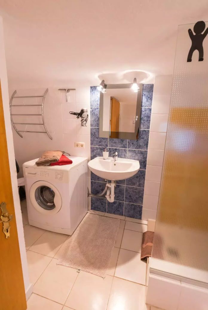 Bany compacte amb rentadora, un lavabo i un mirall.