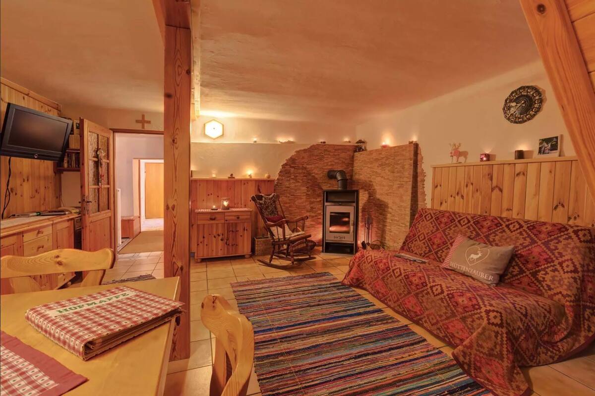 Una sala de estar acogedora con chimenea, muebles de madera y un sofá estampado.
