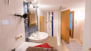 A modern bathroom with a white sink, mirror, and shower.