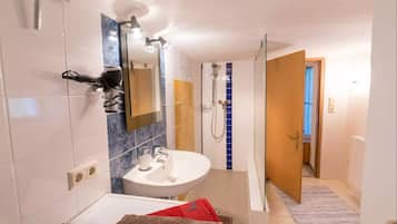 Un baño moderno con un lavamanos, espejo y ducha blancos.
