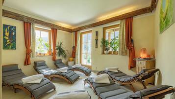 Un cuarto de spa con varias tumbonas, una mesa de masaje y una sauna.
