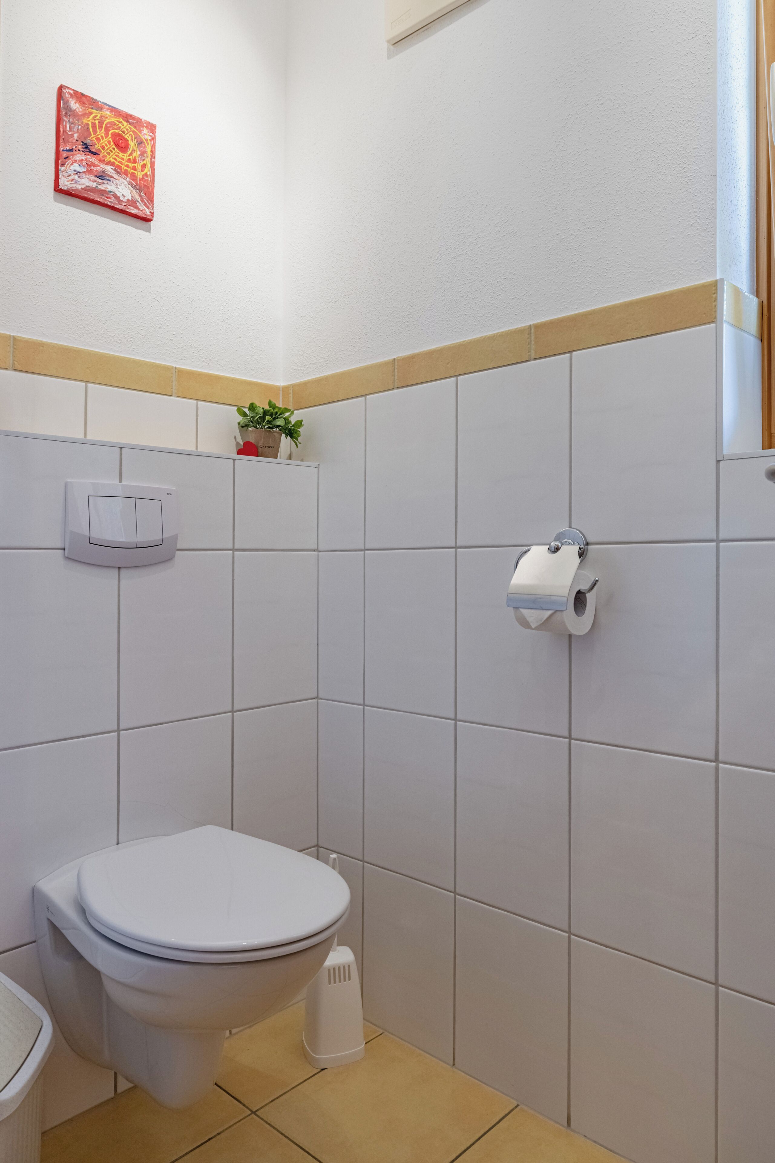 A bathroom with a toilet, a hand dryer, and a paper towel dispenser.
