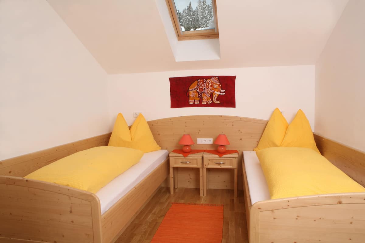 Un dormitorio con dos camas, un tragaluz, una pared roja con un cuadro de elefante y dos lámparas de noche.