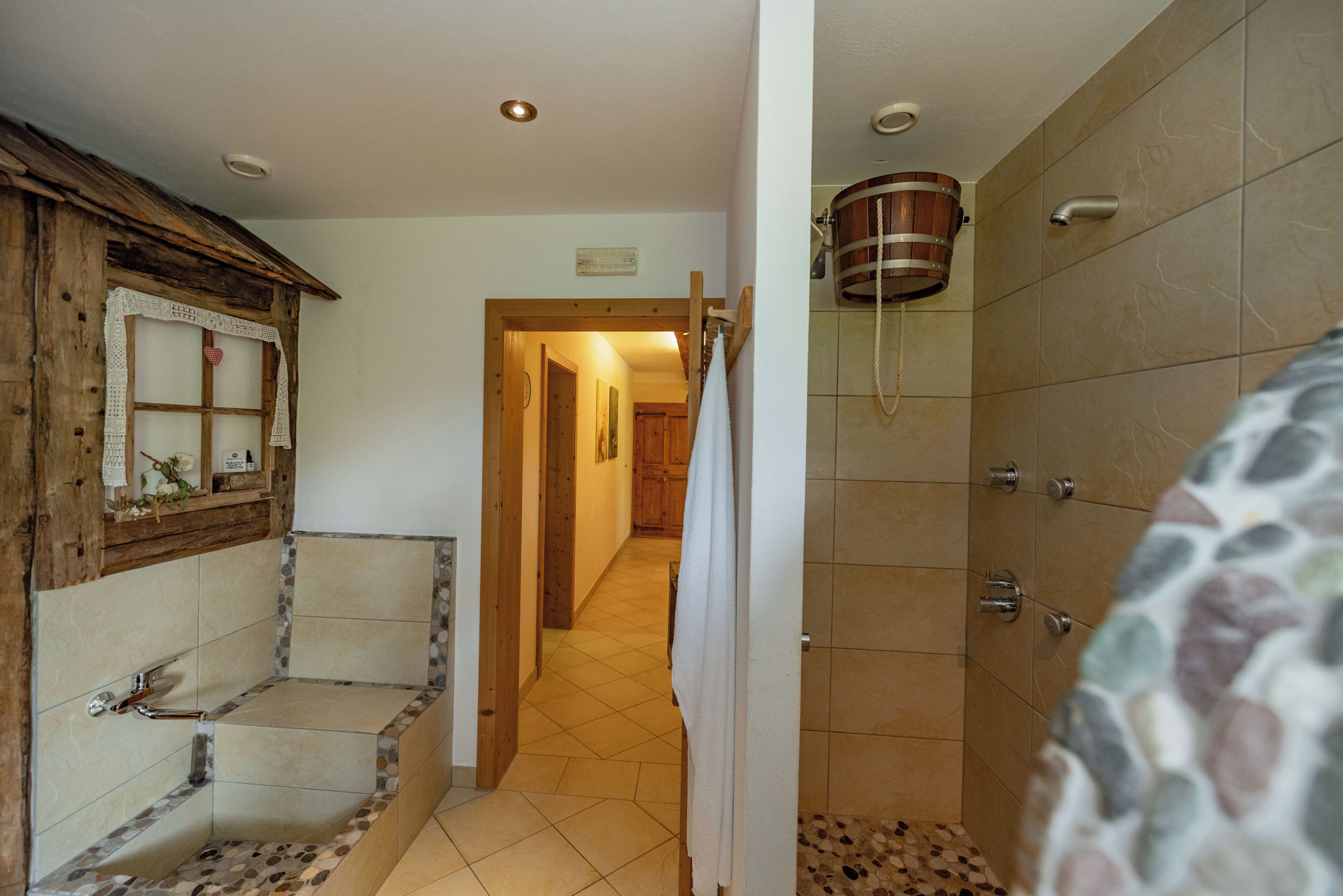 Ein Badezimmer mit einer Holzbadewanne, einer Dusche mit Holzbecken und einem Fliesenboden.