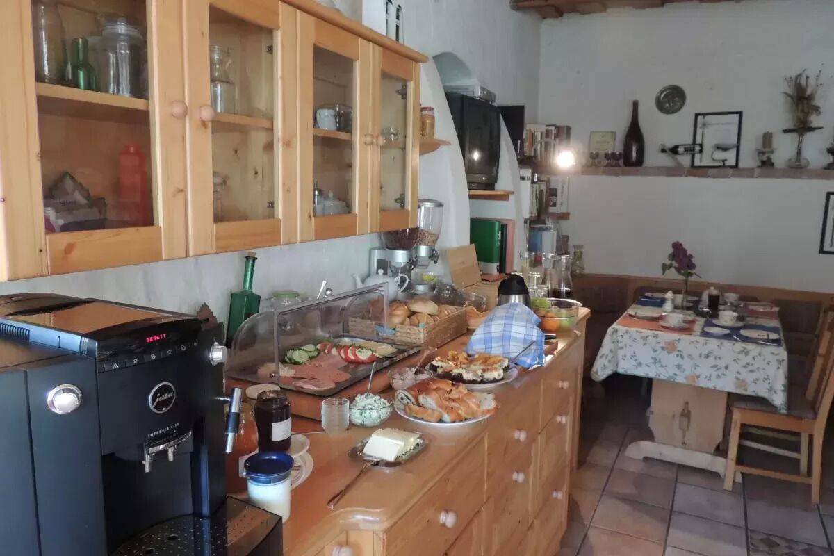 A kitchen with a coffee machine, wooden cabinets, and a dining area with a table set for a meal.