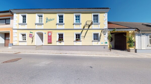 Un bâtiment jaune avec l’inscription « Bohrn » sur la façade, doté d’un escalier, de nombreuses fenêtres et d’une porte.