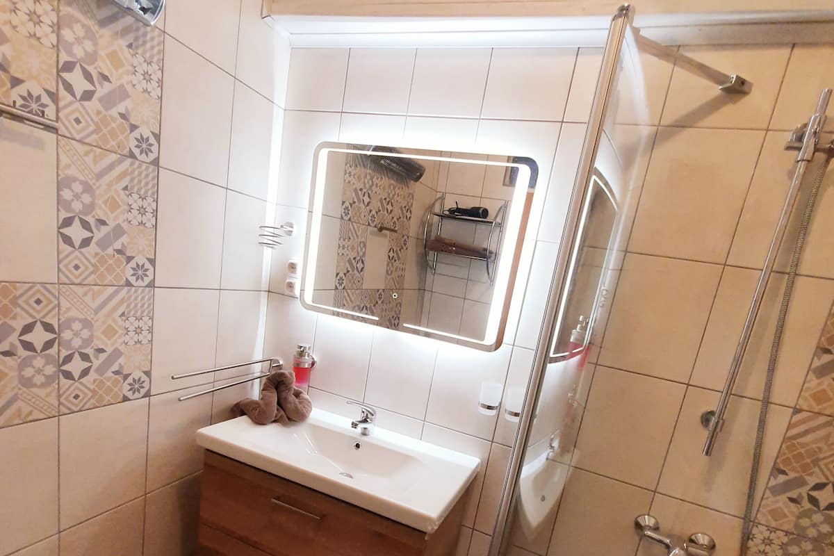 Un baño con lavamanos, espejo y ducha.