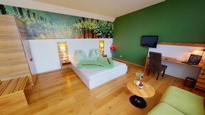 A modern room with a bed, a desk, a TV, and a green wall. - Weingut Himmelbett (Herrnbaumgarten)
