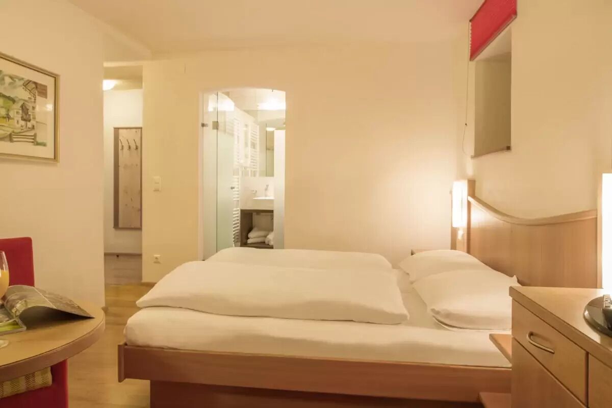 Een slaapkamer met een bed, nachtkastje en spiegel.
