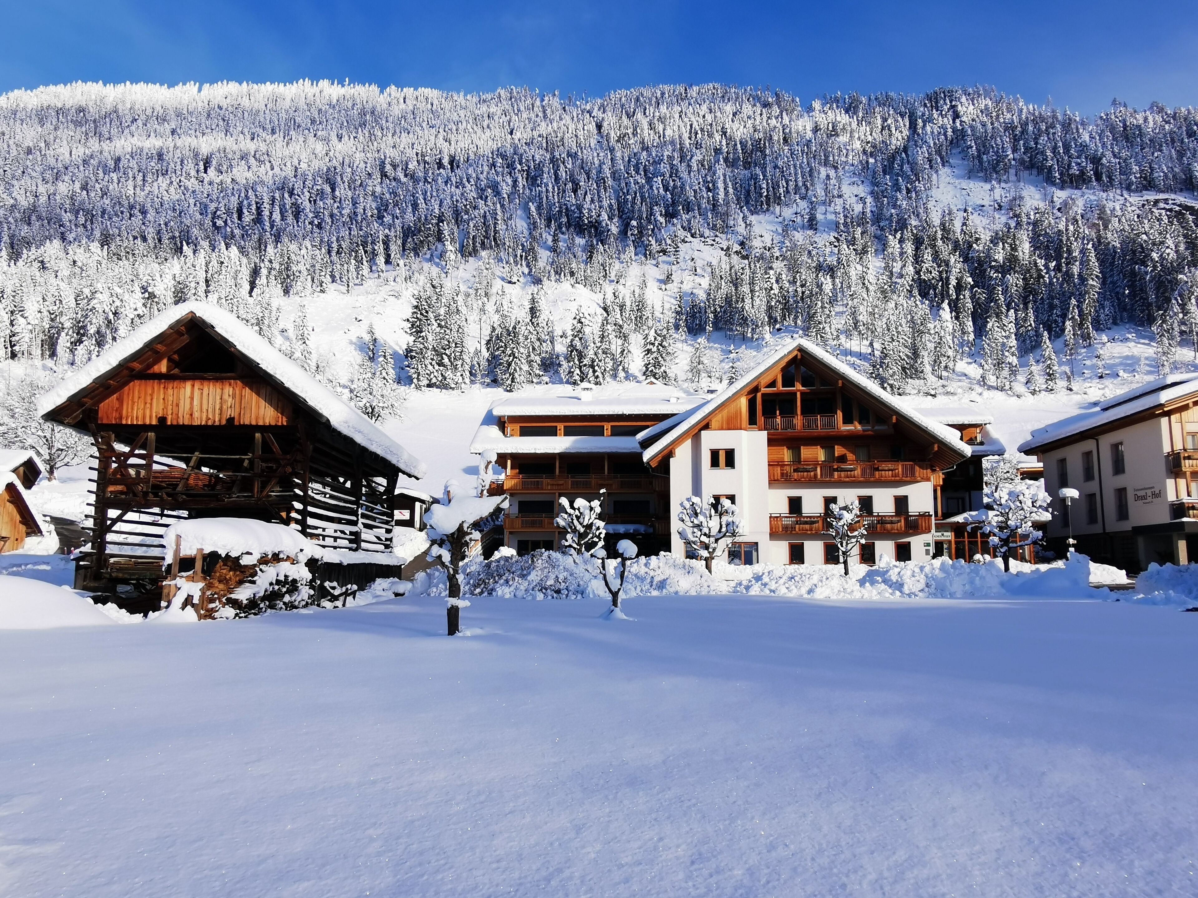 Un chalet de montagne enneigé, avec des cabanes en bois et un grand bâtiment doté de balcons.