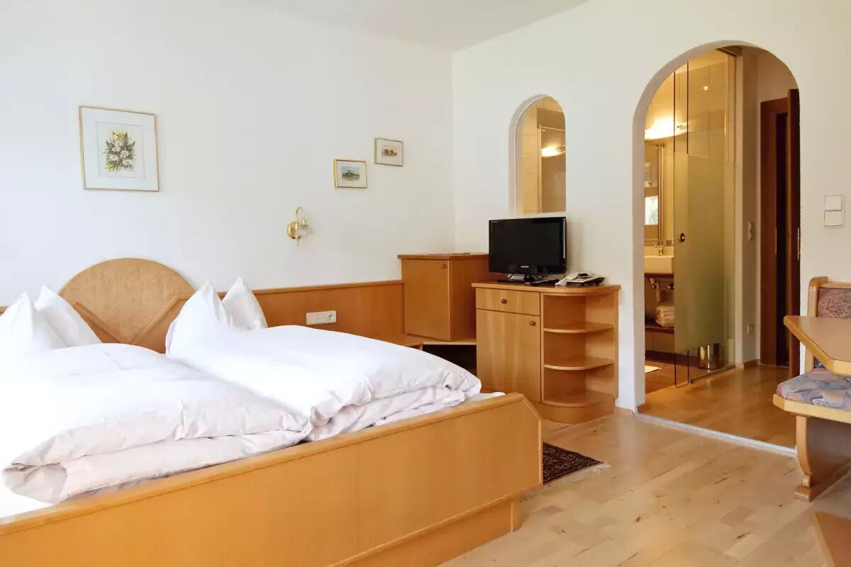 Ein Hotelzimmer mit einem hölzernen Bett, einem Fernseher, einem Schreibtisch und einem Spiegel.